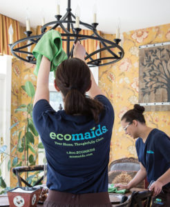 Two maids performing house cleaning services on a dinning room table and chandelier in Ponte Vedra.