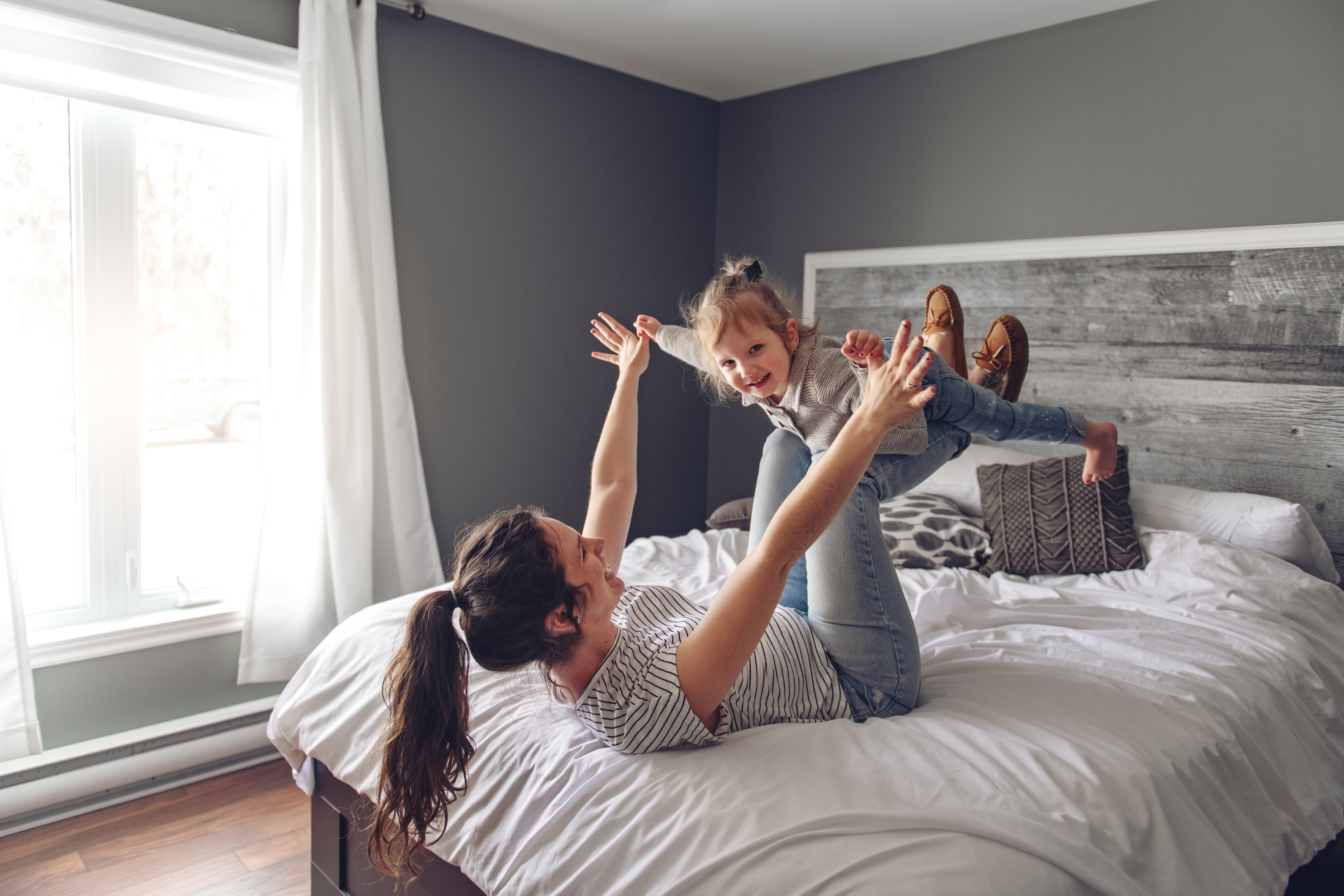 A mom and a girl playing on a bed after receiving ecomaids deep cleaning services in Sparta.